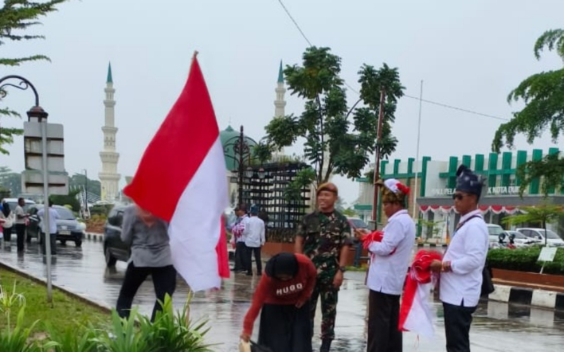 Pelindo Dumai Bersama Forkopimda Guyub Bagikan Bendera Merah Putih di Tengah Hujan