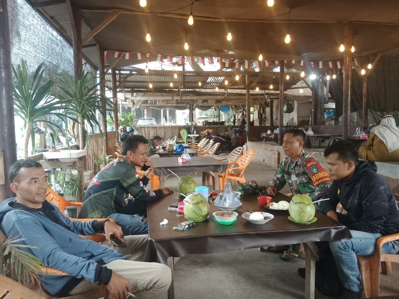 Diguyur Hujan, Babinsa Kodim 0320/Dumai Tetap Laksanakan Komsos Bersama Warga Sungai Geniot