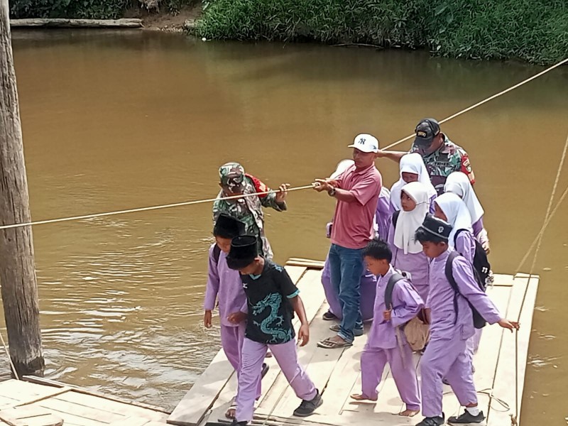 Babinsa Koramil 09/Kemuning Dampingi Anak Sekolah Seberangi Sungai Keritang Menggunakan Rakit