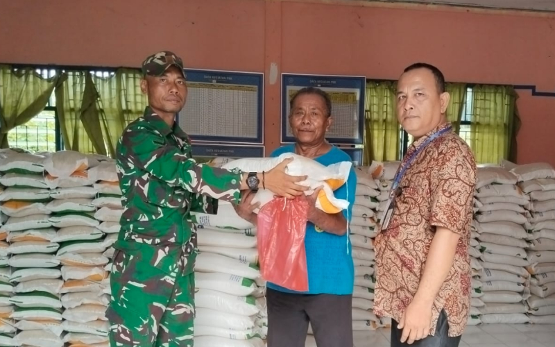 Di Kantor Lurah Tanjung Penyebal, Serda Erwan Dampingi Penyaluran Bantuan Pangan Beras